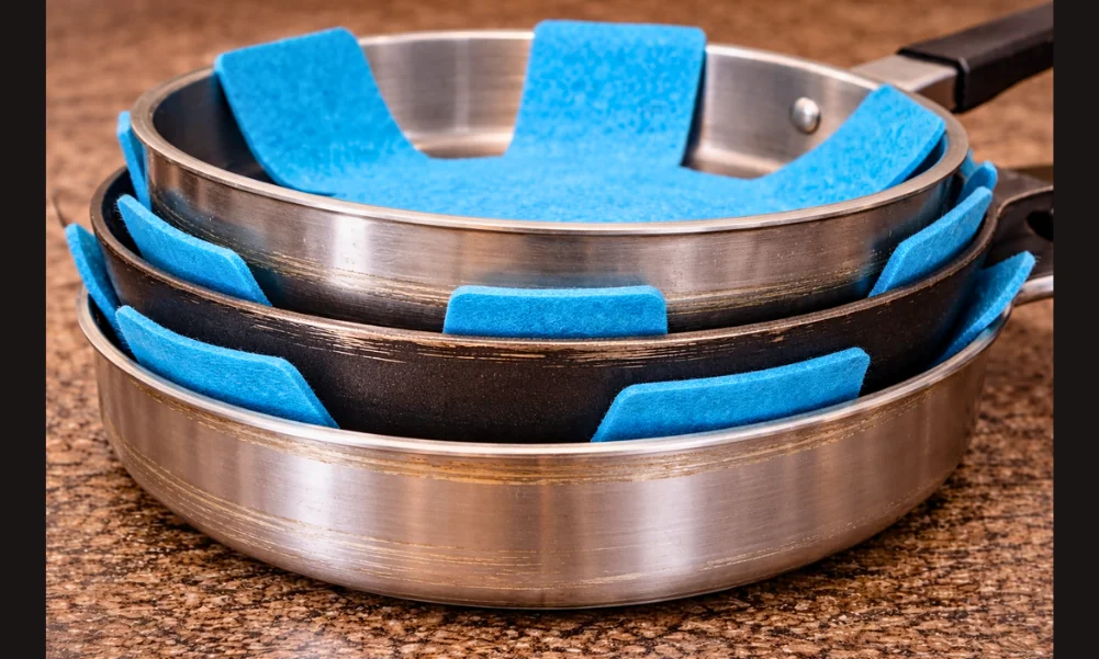 Cookware stacked with protective padding between pans
