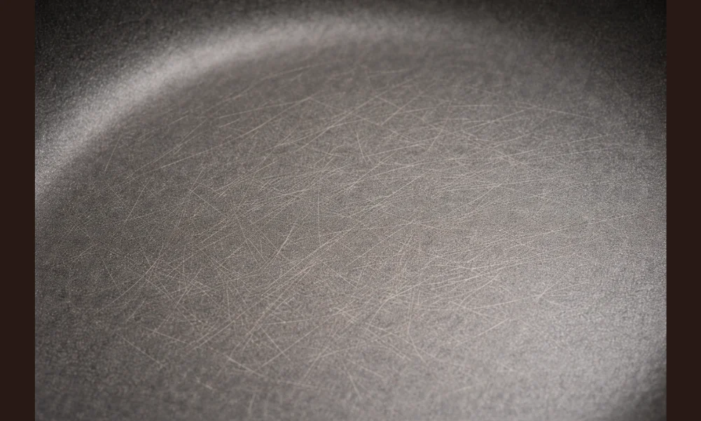 Fine surface wear on cookware caused by repeated cleaning stress