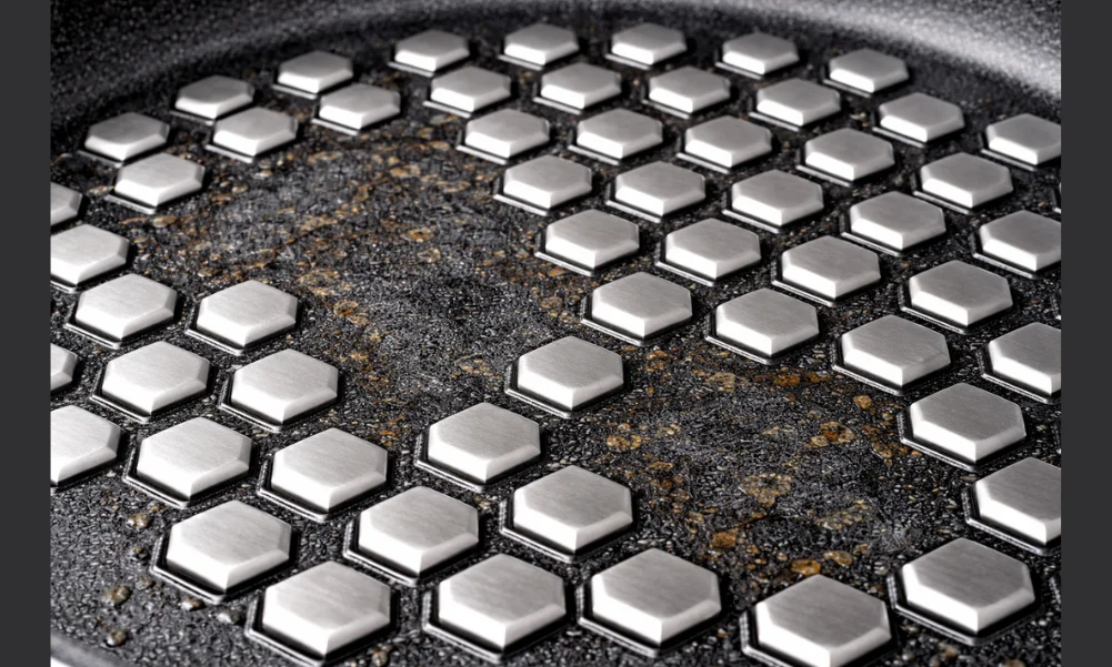 Hybrid cookware showing worn nonstick coating between intact stainless steel ridges