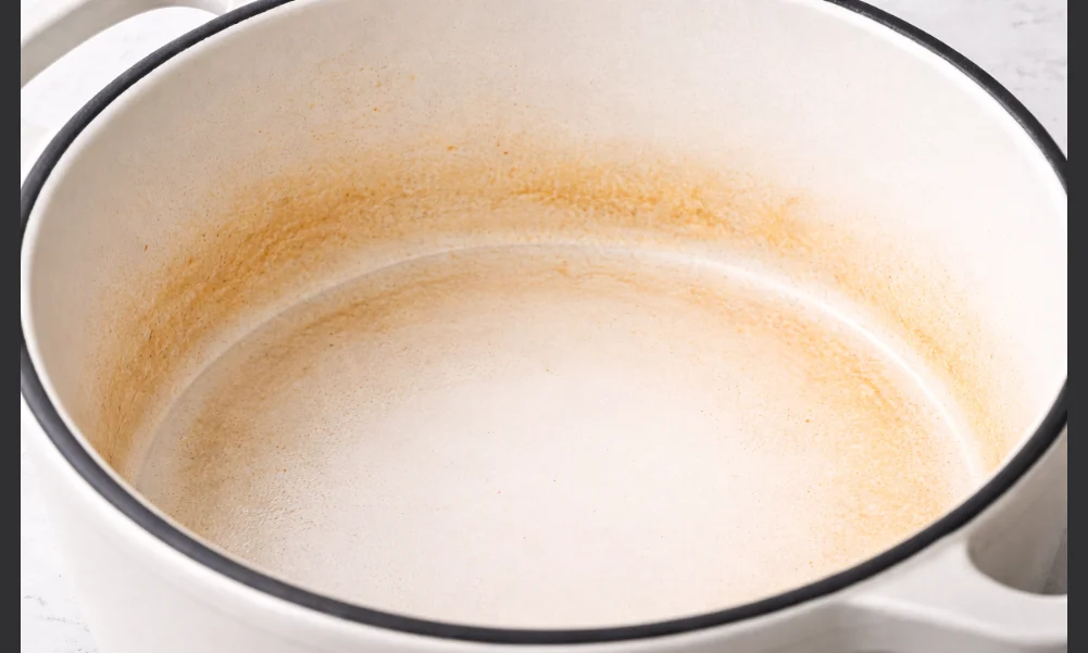 Enameled cast iron cookware with surface staining and intact enamel coating
